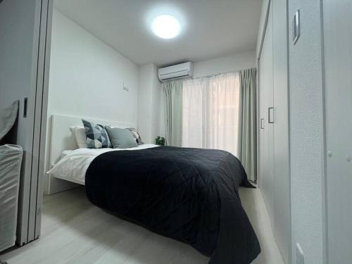 1 dormitorio con 1 cama con manta negra y ventana en Apartment Namba Style 201 en Osaka