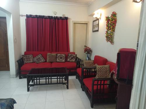 a living room with red couches and a red curtain at Marry House in Dhaka