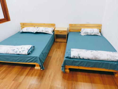 2 camas individuais num quarto com pisos em madeira em Đồi Thông Homestay em Làng Me