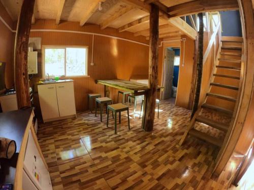 une chambre avec une table et un escalier dans une maison dans l'établissement La madriguera de Yuyito en Conguillio, à Melipeuco