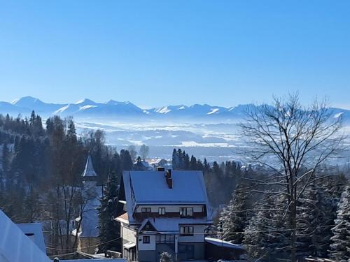 a house on a hill with a snow covered roof at Gorczański Resort Domek w Górach Sauna Jacuzzi in Nowy Targ