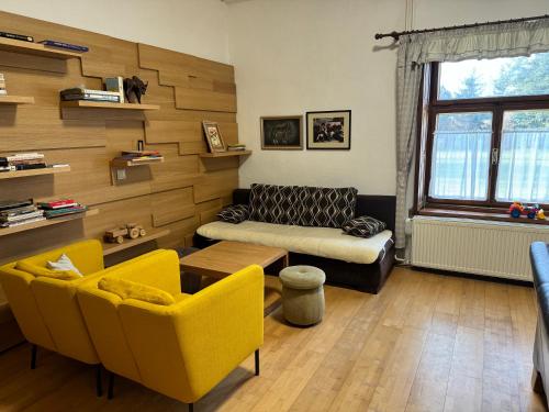 sala de estar con sillas amarillas y sofá en Apartmánové ubytovanie POD DUBOM, en Poľný Kesov
