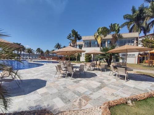 a resort with a pool and chairs and umbrellas at Flat beira lago no centro de BSB in Brasilia