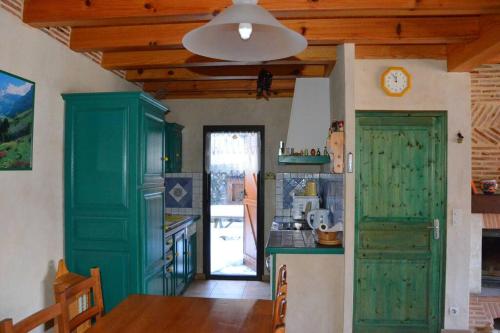 une cuisine avec des placards verts et une horloge murale dans l'établissement Chalet 12 places à 5 mn St Lary, à Camparan