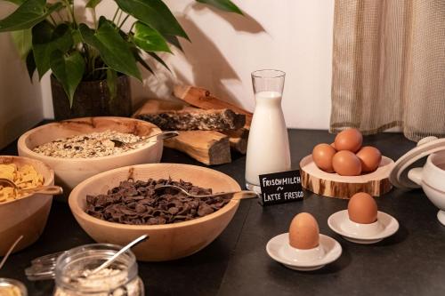 a table with bowls of food and eggs on it at Hotel Bewaller in Obereggen