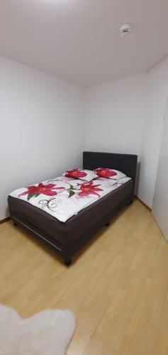 ein Schlafzimmer mit einem Bett mit roten Blumen darauf in der Unterkunft Ferienwohnung zentrale Lage in Idar-Oberstein