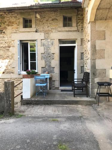 a house with a blue table and a bench on the porch at Gîte Au Moulin Mazaud in Ambazac