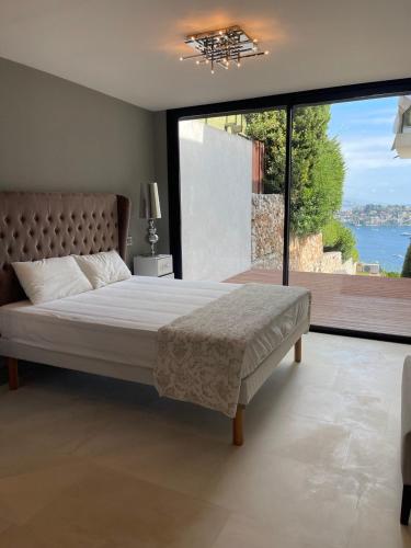 une chambre avec un grand lit et une grande fenêtre dans l'établissement Villa LA ALEGRIA, à Nice