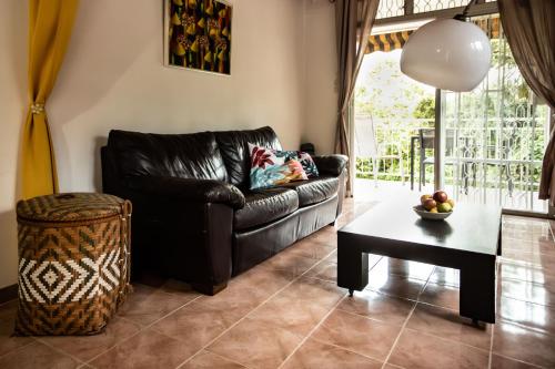 a living room with a black leather couch and a table at Havre de paix à Fort de France in Fort-de-France