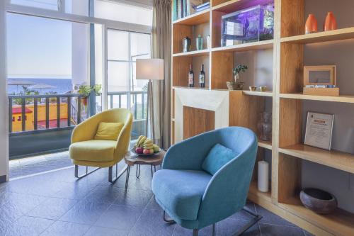 a living room with a blue chair and two yellow chairs at Hotel San Telmo in Santa Cruz de la Palma