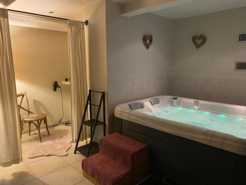 uma casa de banho com uma banheira com um chuveiro e um banco em Le Gîte de l'espace bien être em Libin