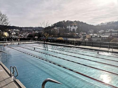 a large swimming pool with a city in the background at Apartments IRIS in Karlovy Vary