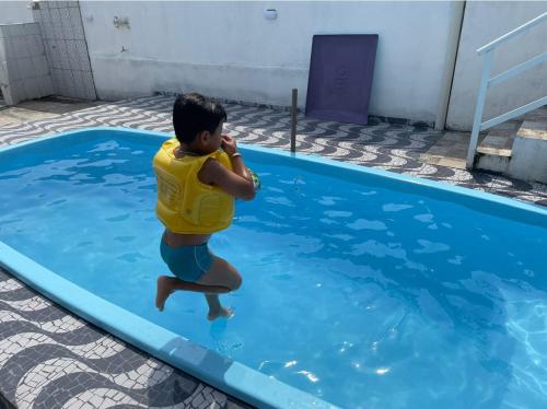 a young boy jumping into a swimming pool at Casa de Praia C/Piscina Matinhos 15 Pessoas 450m do Mar in Matinhos