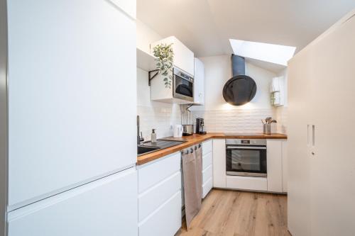 une cuisine avec des armoires blanches et un plancher en bois dans l'établissement L'Evasion Amboise, Sauna Jacuzzi, à Amboise