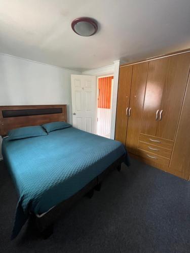 1 dormitorio con 1 cama azul y armarios de madera en Casa Barrio Universitario, en Concepción