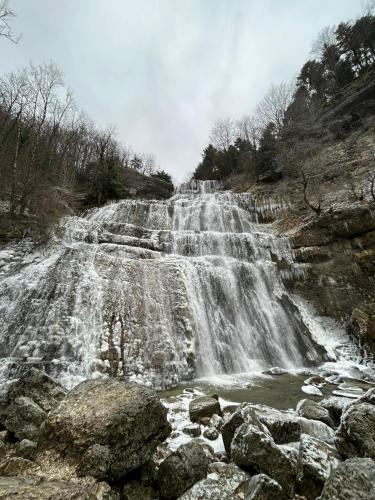 a waterfall on the side of a mountain with rocks at La p'tite maison bois du hérisson in Ménétrux-en-Joux