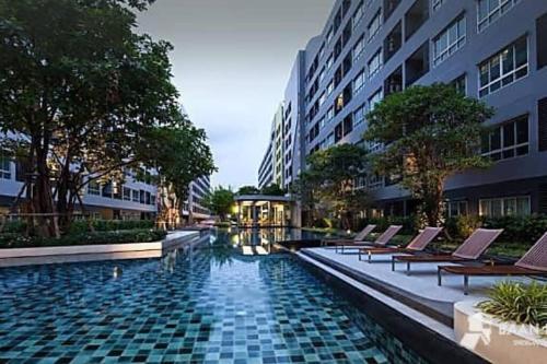 a swimming pool with lounge chairs next to a building at Elio Sukhumvit 64: Chic Space in Bangkok