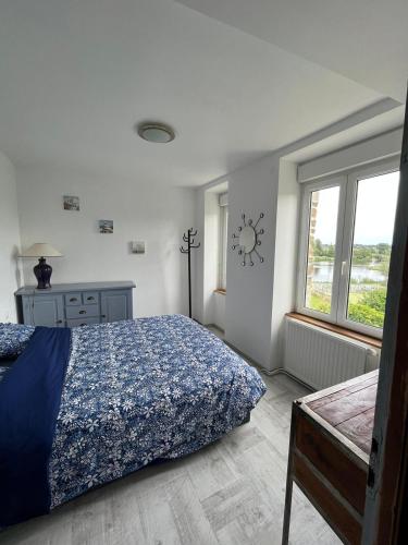 une chambre avec un lit et une horloge au mur dans l'établissement La maison du lac, à Saint-Hilaire-du-Harcouët