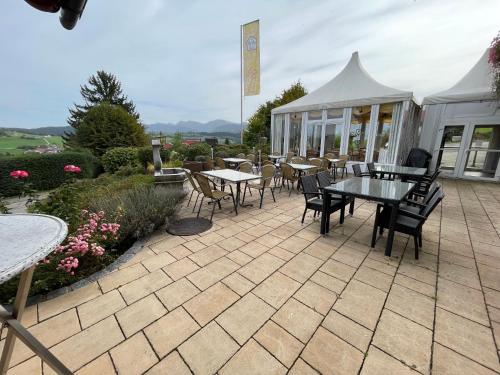 eine Terrasse mit Tischen und Stühlen sowie ein Zelt in der Unterkunft Hotel JMS Holiday Allgäu in Oberreute