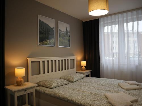 a bedroom with a bed with two lamps and a window at Apartament Nowy Sącz in Nowy Sącz