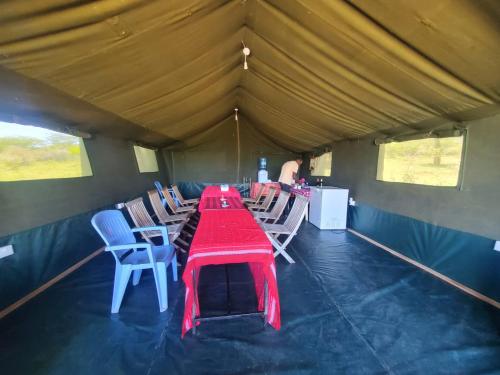 Sekenaniにあるilkerin camp maasai maraのテント内の赤いテーブルと椅子