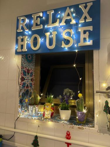 a sign for a hotel with potted plants and lights at Relax House in Bari