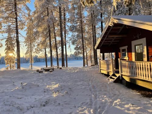 una cabaña de madera en la nieve con un patio cubierto de nieve en Pine Tree Cabin, en Glommersträsk