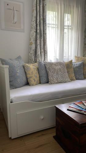 a white couch with pillows sitting in front of a window at Itt és Most - Szent György-hegy in Raposka