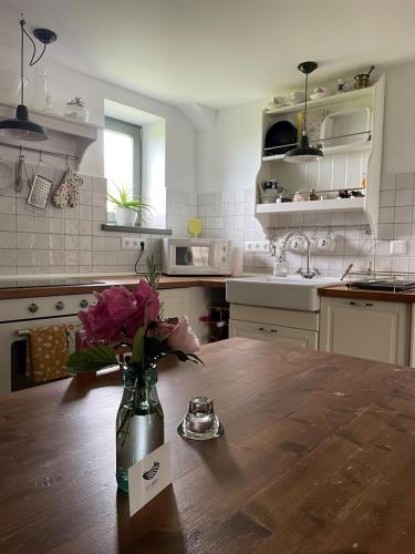 a kitchen with a vase of flowers on a table at Itt és Most - Szent György-hegy in Raposka