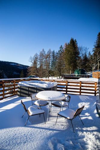 a patio with a table and chairs in the snow at BUNNY GLAMP in Korbielów