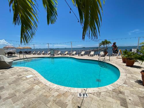 a pool with chairs and a view of the ocean at Waterfront Resort Condo with Balcony Close to Beaches Free Bikes in Dunedin