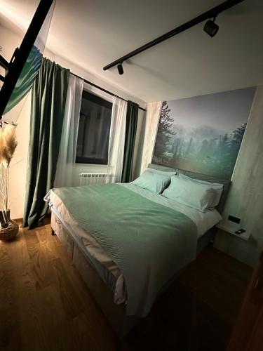 ein Schlafzimmer mit einem großen Bett und einem Gemälde an der Wand in der Unterkunft Apartman 15 in Jahorina