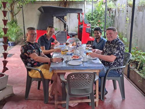 Eine Gruppe von Männern, die an einem Tisch sitzen und Essen essen. in der Unterkunft Mila Rest Garden in Mirissa