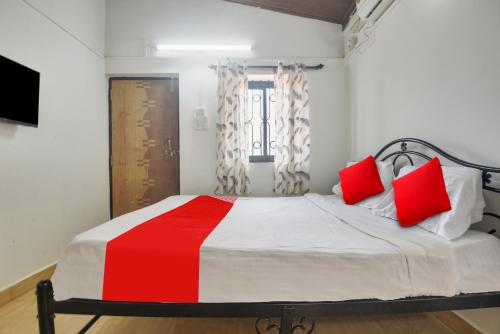 um quarto com uma cama grande e almofadas vermelhas em OYO Pratisha Guest House em Baga