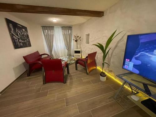 a living room with red chairs and a flat screen tv at Escape Private SPA II in Bad Zurzach