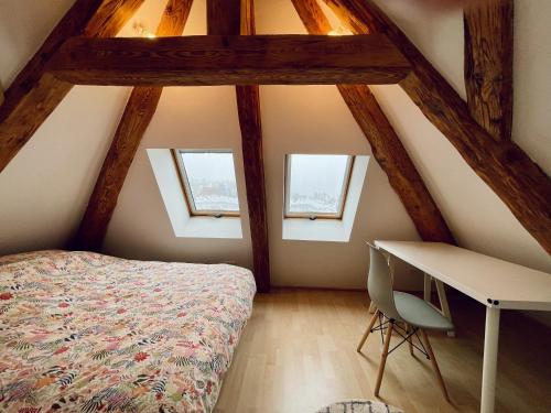 a attic bedroom with a bed and a desk at Duplex + parking gratuit facile in Sainte-Suzanne