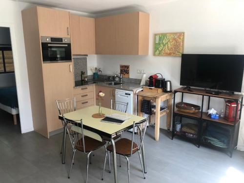 une cuisine avec une table et des chaises ainsi qu'une télévision dans l'établissement Les Ateliers de la Villette Meublé de tourisme classé 2 étoiles T3, à La Ravoire