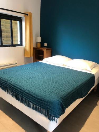 une chambre avec un grand lit avec un mur bleu dans l'établissement Les Ateliers de la Villette Meublé de tourisme classé 2 étoiles T3, à La Ravoire