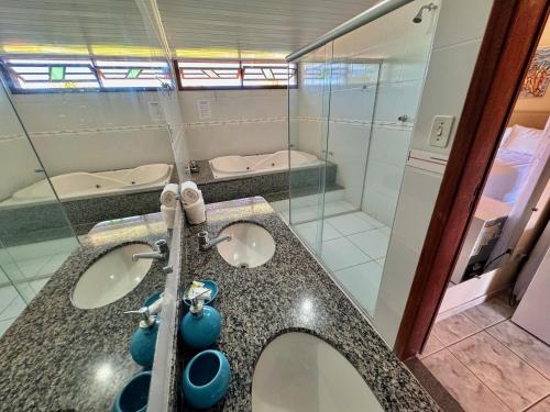 a bathroom with two sinks and a shower at Pousada Recanto do Prado in Prado