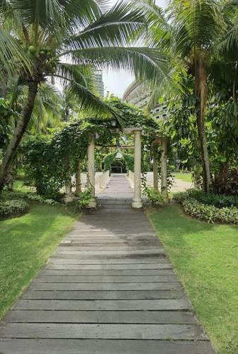 a walkway with palm trees in a park at ForestCity StarView Bay Condo in Kampong Pok Kechil