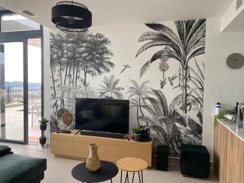 un salon avec une télévision sur un mur orné de palmiers dans l'établissement La casa del león dormido, à Polop