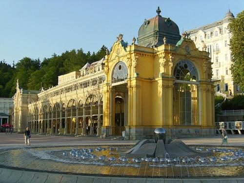 een groot geel gebouw met een fontein ervoor bij Apartmany Cesky Dvur in Mariánské Lázně