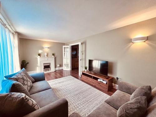 a living room with a couch and a flat screen tv at Stunning 3BR House w/ Parking in Stevenage