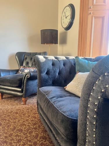 a living room with a blue couch and a clock at Morven Guest House Carnoustie in Carnoustie