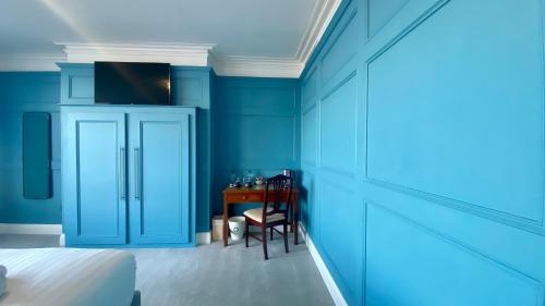 a bedroom with blue walls and a table with a chair at The Fairhaven Hotel in Weymouth