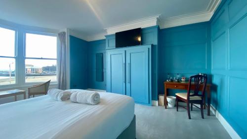 a bedroom with blue walls and a bed with a desk at The Fairhaven Hotel in Weymouth
