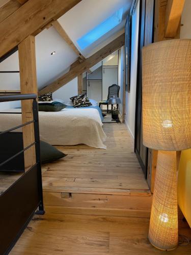 Cette chambre revêtue de parquet comprend un lit et une lampe. dans l'établissement Appartement avec Terrasse & Parking Sarlat centre, à Sarlat-la-Canéda