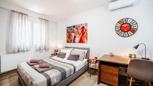 ein Schlafzimmer mit einem Bett, einem Schreibtisch und einer Uhr in der Unterkunft Comfort Zone in Ioannina in Ioannina