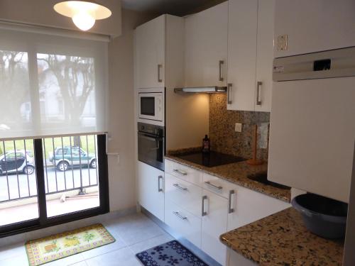 une cuisine avec des placards blancs et une grande fenêtre dans l'établissement Appartement Saint-Jean-de-Luz Centre, à Saint-Jean-de-Luz