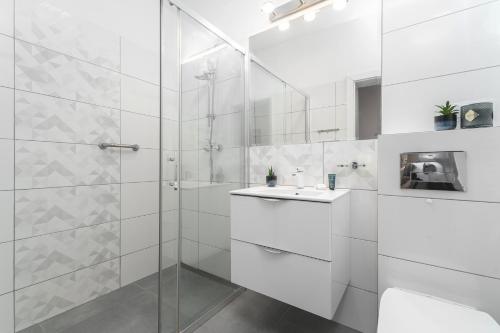 a white bathroom with a shower and a sink at Apartament Niebieski c4 in Pobierowo